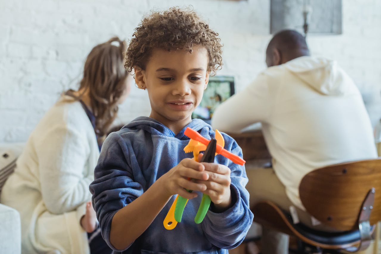 Cheerful black boy with toy tools near multiethnic parents