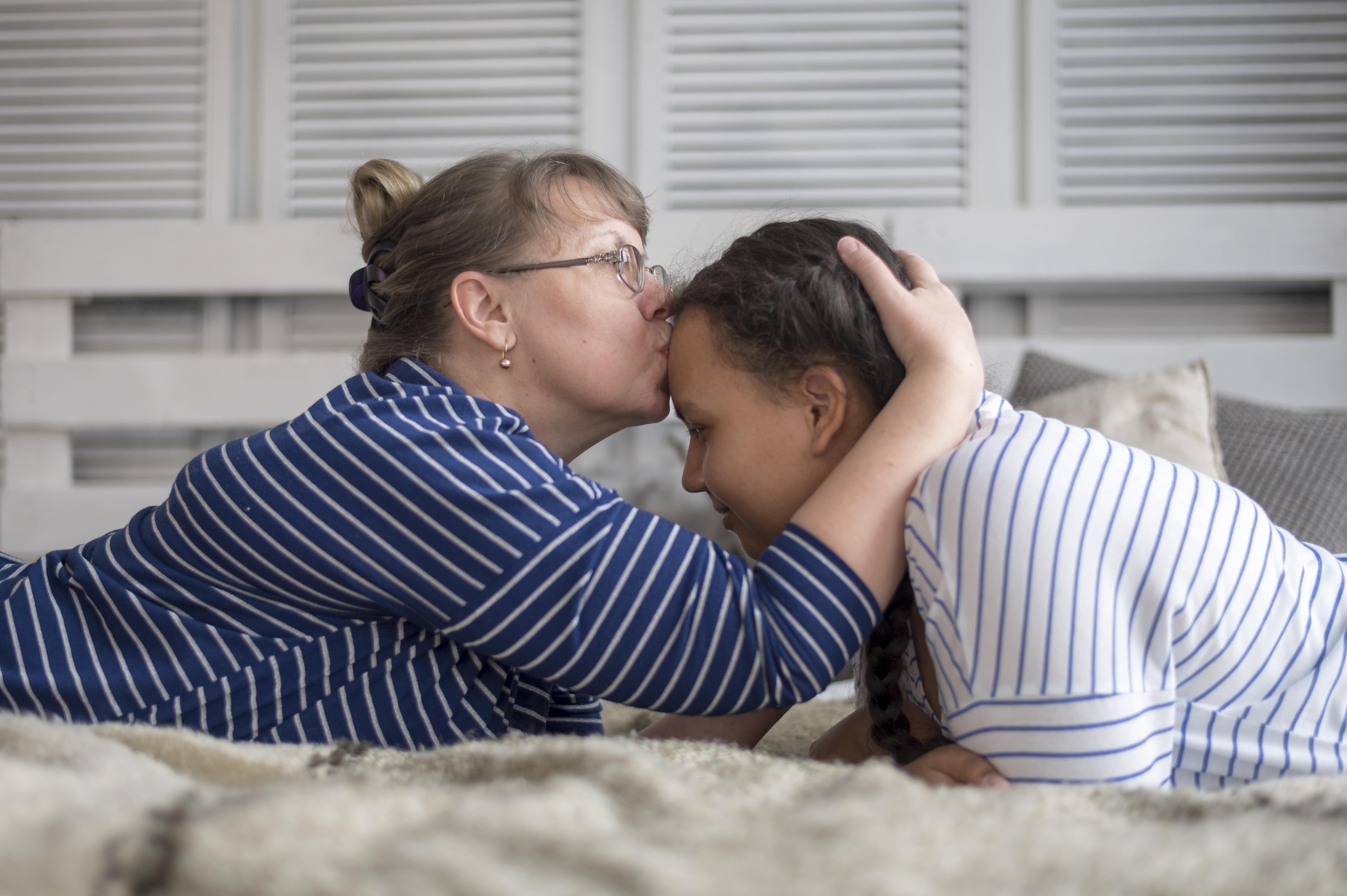 Mom kisses daughter on forehead
