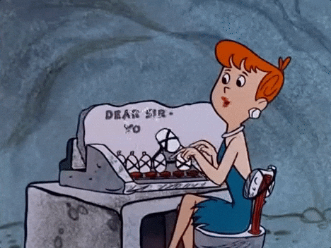 Cartoon woman with orange hair typing on a vintage typewriter at a stone desk with a blue cave-like background.